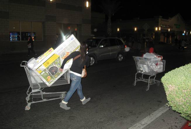 Shoppers leave Walmart with carts of merchandise. The 24-hour retail store sold discounted video games and household products like vacuums, crock pots and blenders discounted for Black Friday.