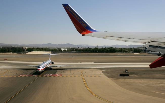 An American Airlines jet waits to taxi as a Southwest Airlines jet takes off from McCarran International Airport in this 2009 file photo.