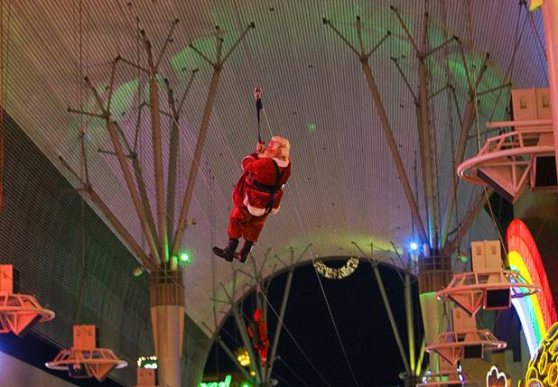 Santa Claus and an elf arrive on Flightlinez, the zipline that travels underneath the Viva Vision canopy, during a Christmas tree-lighting ceremony at Fremont Street Experience in downtown Las Vegas on Tuesday, Dec. 6, 2011.