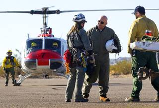Clark County Coroner Michael Murphy, second from right, talks with Metro Police Search and Rescue officers after viewing a helicopter crash site near Lake Mead Thursday, December 8, 2011. Five people were killed when a tour helicopter crashed near the lake Wednesday. .
