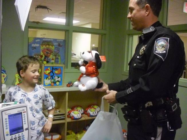 Trooper Bobby Borchardt hands Colin Clifford, 7, toys during NHP's visit to Sunrise Children's Hospital Thursday afternoon.