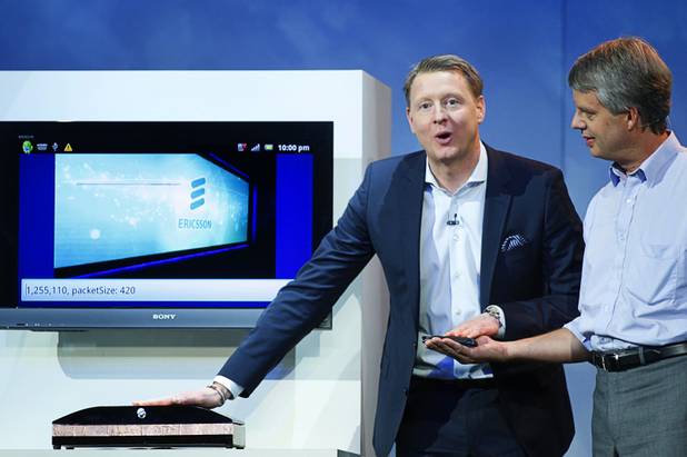 Hans Vestberg (C), president and CEO of the Ericsson Group, transfers a photo from a smartphone to a computer screen using his body during a keynote address at the 2012 International Consumer Electronics Show (CES) in Las Vegas, Nevada, Jan. 11, 2012. Ericsson engineer Anders Stenkvist assists at right. Ericsson demonstrated the new technology, called "capacitive coupling," in which the photograph was transferred from the phone, through the human body, to the screen without using radio signals.