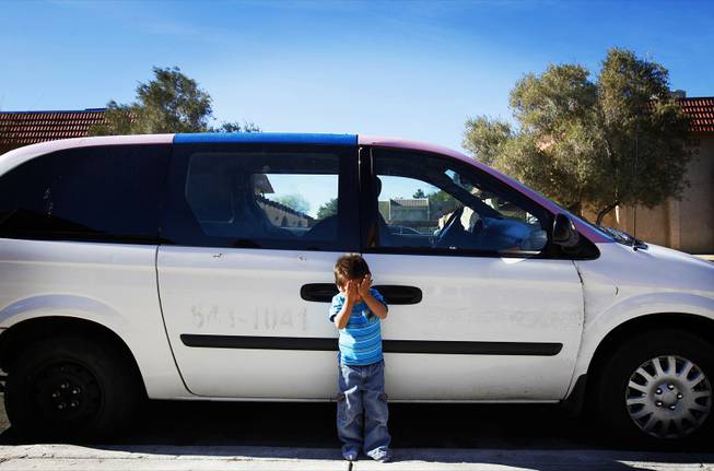 Aldo Ortega, 2, stands in front of the car donated to his family by the church of his mother, Belem Ortega, outside their home in Las Vegas on Jan. 24, 2012.