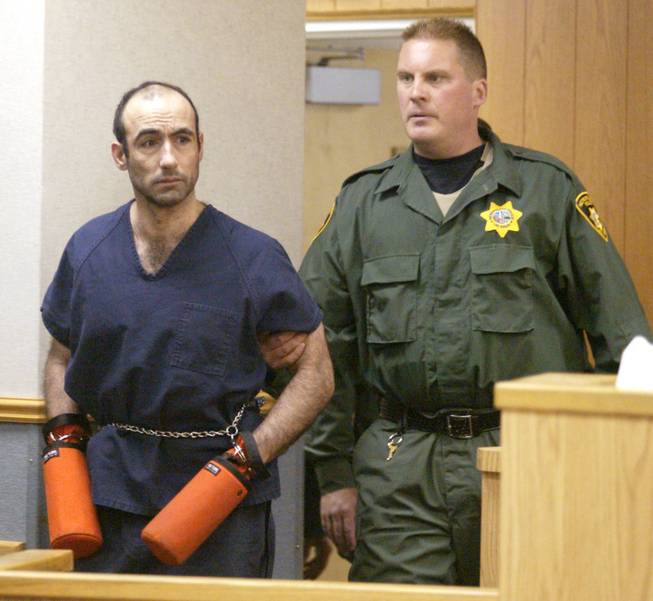 A Las Vegas Metro Police S.E.R.T officer escorts Jose Vigoa into Las Vegas Justice Court on June 6, 2002.