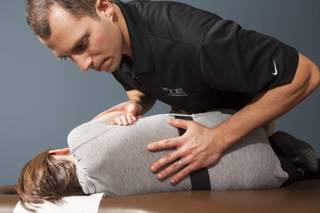 A chiropractic physician from The Joint Chiropractic Clinic demonstrates a procedure on a patient.