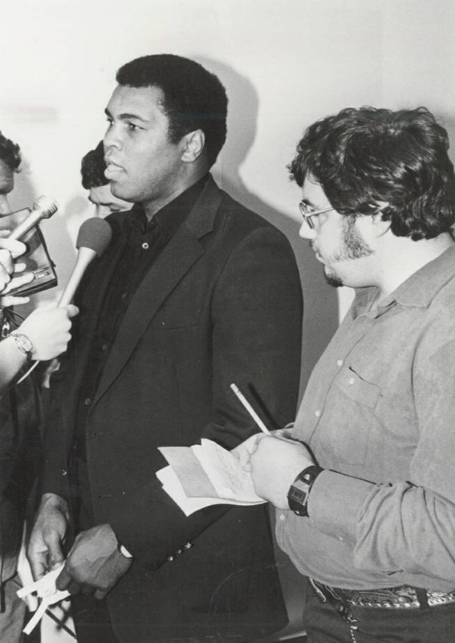 Muhammad Ali talks to reporters after surrendering his Nevada boxing license on Dec. 29, 1980, during a Nevada Athletic Commission hearing in Las Vegas. Ed Koch, former Las Vegas Sun reporter, is standing beside Ali, taking notes.