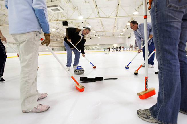 Curling instructor Gary Hunneyman, left, gives lessons on sweeping during a practice session of the Las Vegas Curling Club at the Las Vegas Ice Center on West Flamingo Roadon Feb 12, 2012. Dave Greenman is at right.