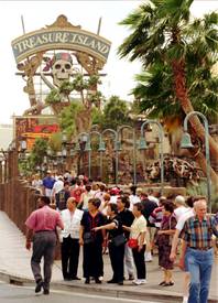 Tourists walk by the old Treasure Island sign along the Las Vegas Strip in this 1997 file photo.
