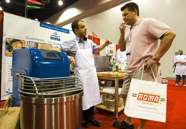 Inventor Roberto Brisciani, left, of Thinking Foods explains the features of the Smart Dough System machine to restaurant owner Celestino Gencarelli during the International Pizza Expo at the Las Vegas Convention Center Wednesday, March 14, 2012.