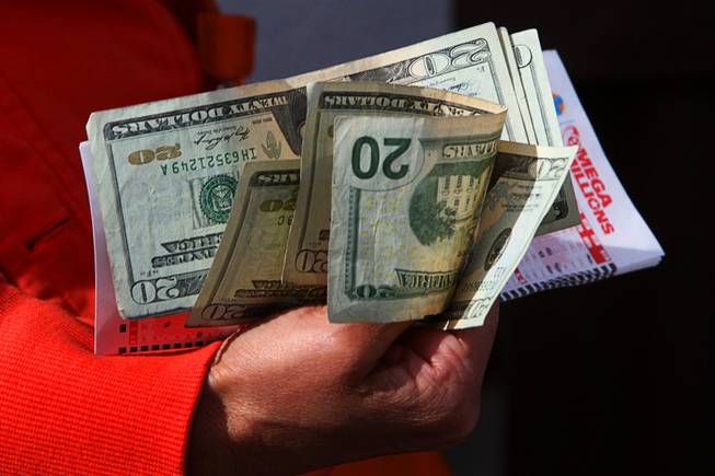 A woman holds her cash and lottery picks as she ...