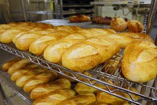 Loaves of sour dough bread cool on racks at Bon Breads, a wholesale artisan bakery, Thursday, April 19, 2012.