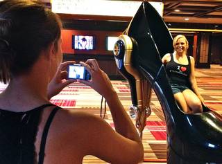 A visitor at Cosmopolitan gets her picture taken while sitting inside one of the giant shoe sculptures by artist Roark Gourley.