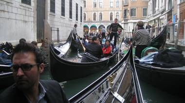 A gondola is navigated through a busy canal in Venice. The guy in the foreground is Tony Moreno.