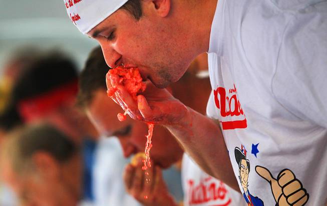 Returning champion Sean Gordon shoves liquid soaked hot dogs into ...