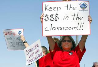 Debra Cooley, a kindergarten teacher at Steele Elementary School, holds up a sign before a Clark County School Board meeting at the Edward Greer Education Center on East Flamingo Road Wednesday, May 16, 2012. The board approved a final budget that will lay off 1,015 positions in order to balance the budget.