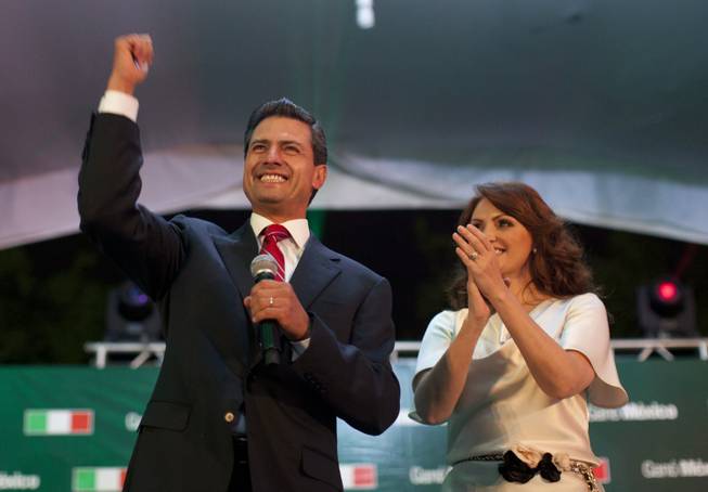 Enrique Peña Nieto, presidential candidate for the Revolutionary Institutional Party, left, speaks to supporters accompanied by his wife, Angelica Rivera, at the party's headquarters in Mexico City, July 2, 2012.