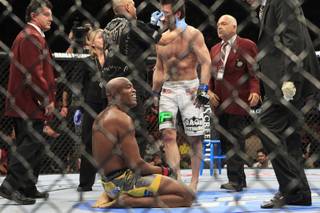 Champion Anderson Silva smiles while Chael Sonnen is attended to after Silva scored a second round TKO during their fight at UFC 148 Saturday, July 7, 2012.