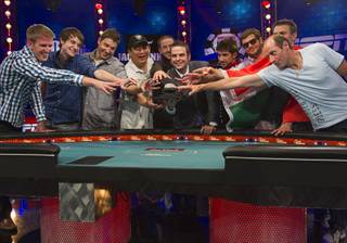 Members of the October Nine reach for the championship bracelet held by Jack Effel, World Series of Poker tournament director, after making the final table in the World Series of Poker's $10,000 buy-in, no-limit Texas Hold'em main event at the Rio Monday, July 17, 2012. From left are: Russell Thomas, Jacob Balsiger, Jeremy Ausmus, Steven Gee, Greg Merson, Jesse Sylvia, Robert Salaburu, Andras Koroknai and Michael Esposito. All the players are from the United States except Koroknai who is from Hungary.