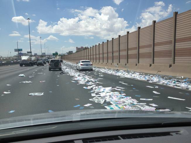 Papers litters Interstate 15 between Sahara Avenue and Charleston Boulevard after a box fell from a truck and was hit by a bus Tuesday, July 24, 2012.