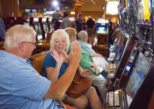 Slot player Babs Duncan gets a high five from her husband Jack after picking the winning horse and winning $70 in bonus credits in a virtual horse race at the South Point Thursday, July 26, 2012. The South Point is the first casino in Nevada to implement the virtual race by Bally Technologies. Winners will split a total prize pool of $30,000 in bonus credits on Thursdays.