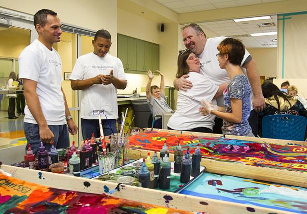 Jeff Lalley a public area manager at the Cosmopolitan, gets a hug from Opportunity Village client Clarissa, while volunteering at the Opportunity Village Engelstad Campus on South Buffalo Drive Monday, July 29, 2012. Client Amanda looks on at right. Also from the Cosmopolitan are Doug Filter, left, and Lorenzo Vierra. Corporate volunteers come to the campus once a month to work with clients, said art mentor Tim Ortiz.