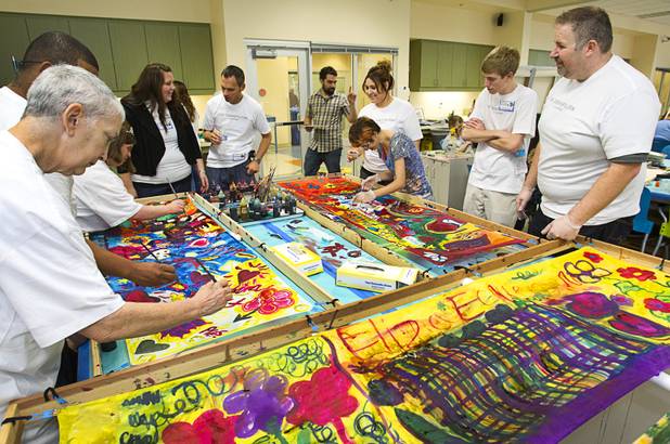 Volunteers from the Cosmopolitan help clients paint silk scarfs at the Opportunity Village Engelstad Campus on South Buffalo Drive Monday, July 29, 2012. Corporate volunteers come to the campus once a month to work with clients, said art mentor Tim Ortiz.