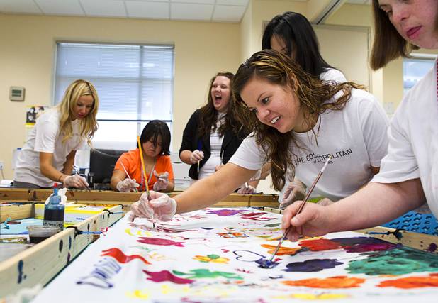 Maylea Graham, center, a volunteer from the Cosmopolitan helps paint a silk scarf with an Opportunity client at the Opportunity Village Engelstad Campus on South Buffalo Drive Monday, July 29, 2012. Corporate volunteers come to the campus once a month to work with clients.