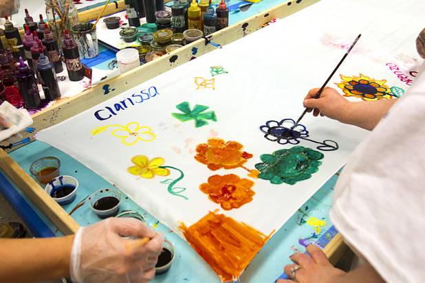 Clarissa, an Opportunity Village client, paints a silk scarf at the Opportunity Village Engelstad Campus on South Buffalo Drive Monday, July 29, 2012. Corporate volunteers come to the campus once a month to work with clients.