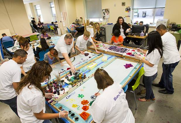 Volunteers from the Cosmopolitan help clients paint silk scarfs at the Opportunity Village Engelstad Campus on South Buffalo Drive Monday, July 29, 2012. Corporate volunteers come to the campus once a month to work with clients, said art mentor Tim Ortiz.