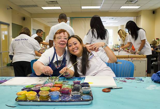 Opportunity Village client Gloria, left, poses with volunteer Kelly Racine, a Cosmopolitan restaurant sales manager, at the Opportunity Village Engelstad Campus on South Buffalo Drive Monday, July 29, 2012. Corporate volunteers come to the campus once a month to work with clients, said art mentor Tim Ortiz.