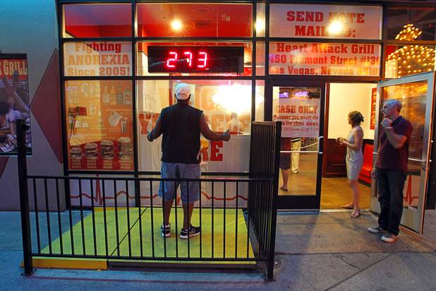 Troy Jackson of Seattle weighs himself on a scale outside the Heart Attack Grill at the Neonopolis mall in downtown Las Vegas Wednesday, August 1, 2012.