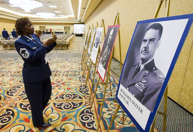 Air Force Sr. Master Sgt. Madalina Bramwell takes photos of a display during the International Black Aerospace Council convention at the Las Vegas Hotel Wednesday, August 1, 2012. At right is a photo of Benjamin Oliver Davis Jr. commander of the World War II Tuskegee Airmen and the first African-American U.S. Air Force general.