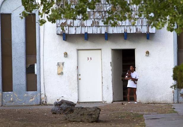 A woman holds a child outside a unit at the Desert Gardens Condominiums complex near Martin Luther King Jr. Boulevard and Bonanza Road Monday, Aug. 6, 2012. Of 147 units in the complex, only about 50 are occupied, said a Metro Police officer.