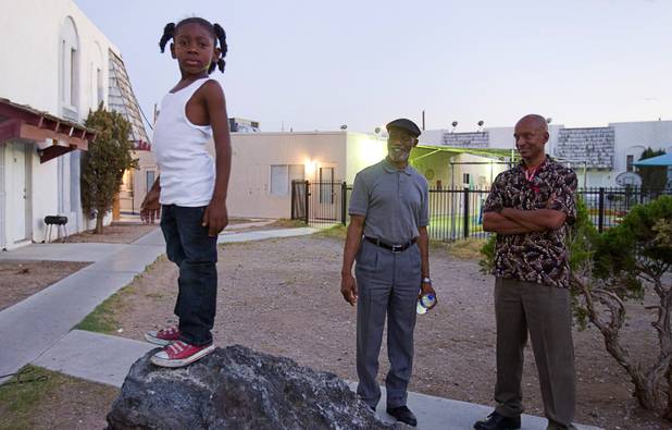 Ky'Shaun Estes, 5, plays on a boulder as community leaders Mujahid Ramadan (center) and Alonzo M. Jones (right) look on at the Desert Gardens Condominiums complex near Martin Luther King Jr. Boulevard and Bonanza Road Monday, Aug. 6, 2012.