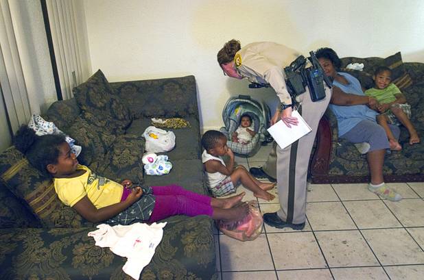 Metro Police Officer T. Brosnahan visits with children in an apartment at the Desert Gardens Condominiums complex near Martin Luther King Jr. Boulevard and Bonanza Road Monday, Aug. 6, 2012.
