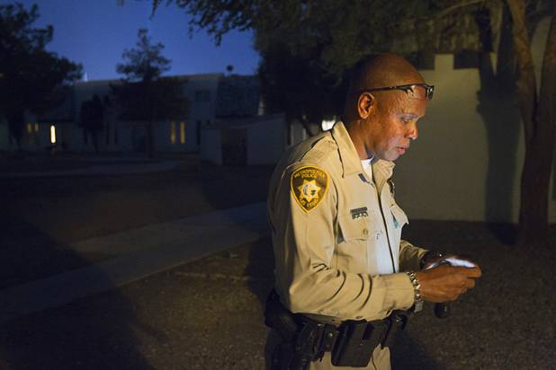 Metro Police Officer Jeff Willis check his phone at the Desert Gardens Condominiums complex near Martin Luther King Jr. Boulevard and Bonanza Road Monday, Aug. 6, 2012.