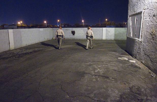 Metro Police officers Jeff Willis and T. Brosnahan walk the parameter of the Desert Gardens Condominiums complex near Martin Luther King Jr. Boulevard and Bonanza Road Monday, Aug. 6, 2012. Holes in the walls are used as footholds for suspects that want to quickly scale the walls and evade police, they said.