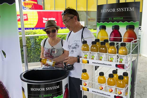Nilton and Sumico Abel of Brazil look over bottles of tea at a self-service Honest Tea kiosk on the Las Vegas Strip Monday, Aug. 13, 2012. Observers from the tea company watched from a distance and recorded how many people paid for the tea and how many did not. The Honest Cities social experiment is being held in 50 locations in 30 cities.