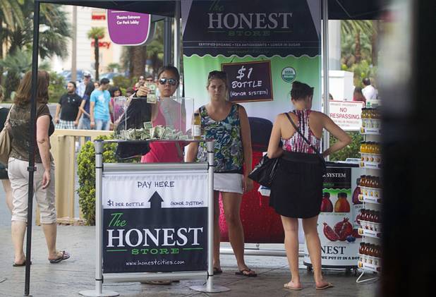 Women pay for bottles of tea at a self-service Honest Tea kiosk on the Las Vegas Strip Monday, Aug. 13, 2012. Observers from the tea company watched from a distance and recorded how many people paid for the tea and how many did not. The Honest Cities social experiment is being held in 50 locations in 30 cities.