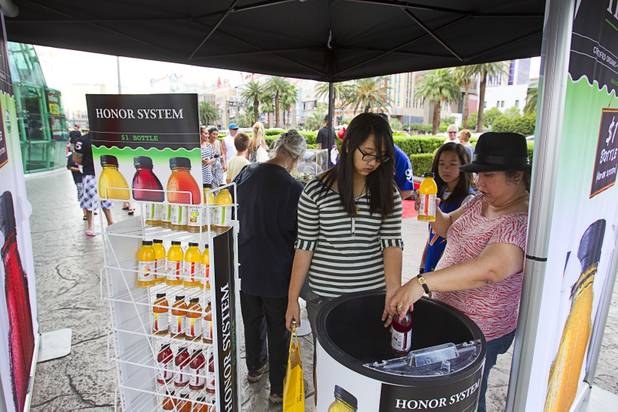Canadian tourists Alyanah Evangelista, 12, and her mother Mildred Evangelista pick out tea at a self-service Honest Tea kiosk on the Las Vegas Strip Monday, Aug. 13, 2012. Observers from the tea company watched from a distance and recorded how many people paid for the tea and how many did not. The Honest Cities social experiment is being held in 50 locations in 30 cities.