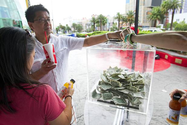 Canadian tourists Johnny and Joanne (no last name provided) p[ay for tea at a self-service Honest Tea kiosk on the Las Vegas Strip Monday, Aug. 13, 2012. Observers from the tea company watched from a distance and recorded how many people paid for the tea and how many did not. The Honest Cities social experiment is being held in 50 locations in 30 cities.