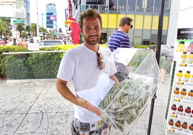 Ryan Vande Griendt , Southwest region marketing manager for Honest Tea, holds a box of cash as managers break down a self-service Honest Tea kiosk on the Las Vegas Strip Monday, Aug. 13, 2012. Vande Griendt and other managers watched the kiosk from a distance and recorded how many people paid for the tea and how many did not. The Honest Cities social experiment is being held in 50 locations in 30 cities.