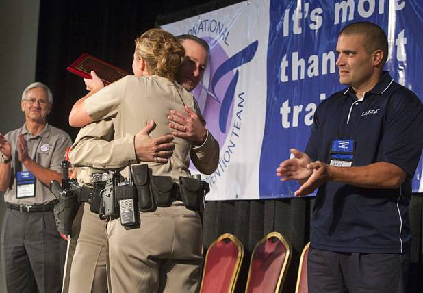 Metro Police Officer Booke Lavin is congratulated by Metro Officer Jeremy Levy, 2006 CIT Officer of the Year, after receiving the award for Crisis Intervention Team (CIT) Officer of the Year during a CIT International awards luncheon at the South Point Tuesday, Aug. 21, 2012. Sgt. Andy Suvada, of Streetsboro, Ohio, 2011 CIT Officer of the Year, applauds at right.  Lavin was honored with the award after calming a suicidal man and then following up to make sure the man received a variety of social services.