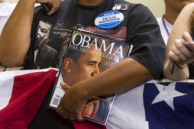 A woman holds a book on President Barack Obama as she waits for the president to speak at a rally at Canyon Springs High School in North Las Vegas Wednesday, Aug. 22, 2012.