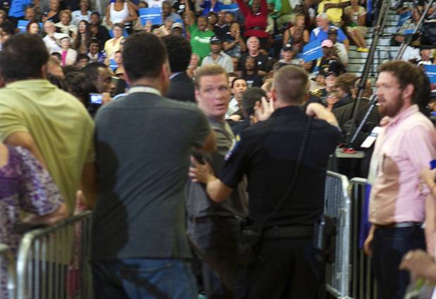 An unidentified man, center, is escorted from the rally by security as President Barack Obama speaks at a rally at Canyon Springs High School in North Las Vegas Wednesday, Aug. 22, 2012.
