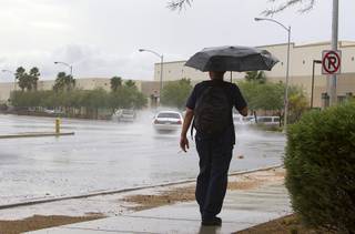 A man walks in the rain on North Pecos Road in North Las Vegas Wednesday, Aug. 22, 2012.