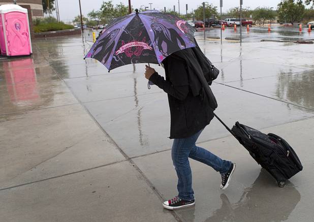 A woman shields herself from the rain as she heads into Canyon Springs High School in North Las Vegas Wednesday, Aug. 22, 2012.