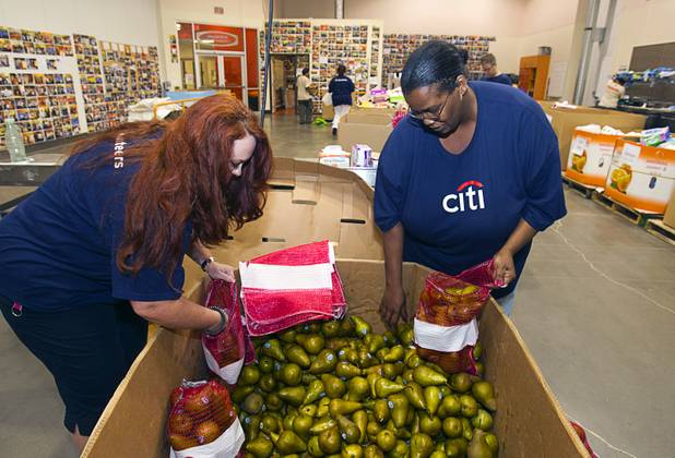 Jill Clark, left, and Amelia Brewer, volunteers from Citibank, bag pears in the Volunteer Room at the Three Square Food Bank Wednesday, Aug. 22, 2012.