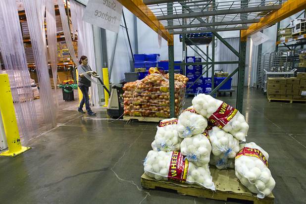 Warehouse assistant Stacey Pybus takes a load of onions into a cooler at the Three Square Food Bank Wednesday, Aug. 22, 2012.