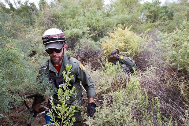 Metro Search and Rescue volunteers Sean Smith and Rochelle Cowan make their way through heavy brush during a search for Henderson teen William Mootz near the Duck Creek channel, north of Sam Boyd Stadium Thursday, Aug. 23, 2012. Mootz, a Green Valley High School student, was swept away by storm run off in the Pittman Wash Wednesday.